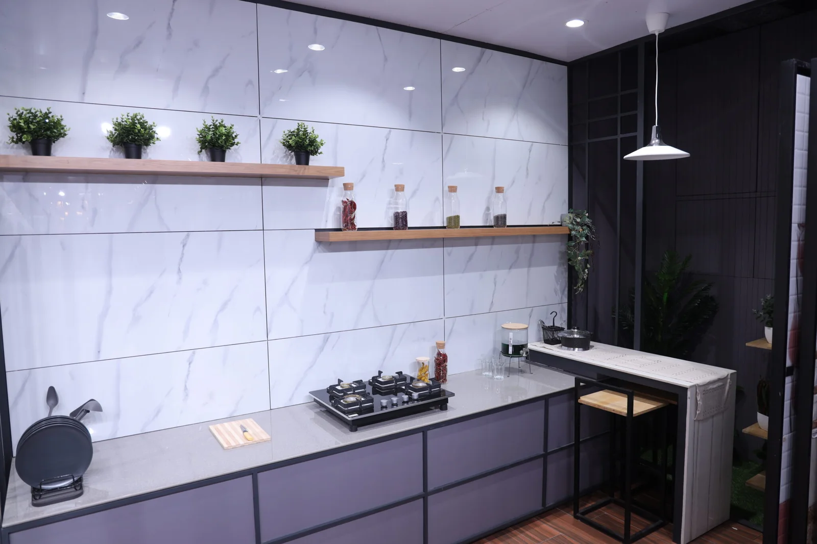 Kitchen display with marble-look wall tiles, a gas hob and a counter at the Devaki Ceramics showroom